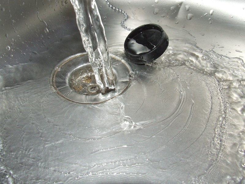 Avlopp i diskbänk där vatten rinner ner