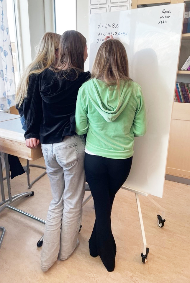 Tre elever samarbetar vid whiteboardtavla